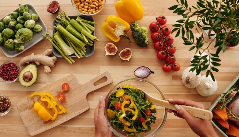 Top view of fresh vegetables and salad preparation on a wooden table, perfect for healthy eating concepts.